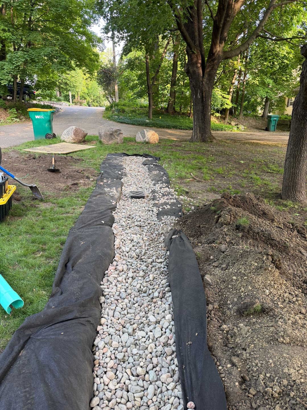 Landscaping project featuring a gravel path lined with black fabric in a green yard.